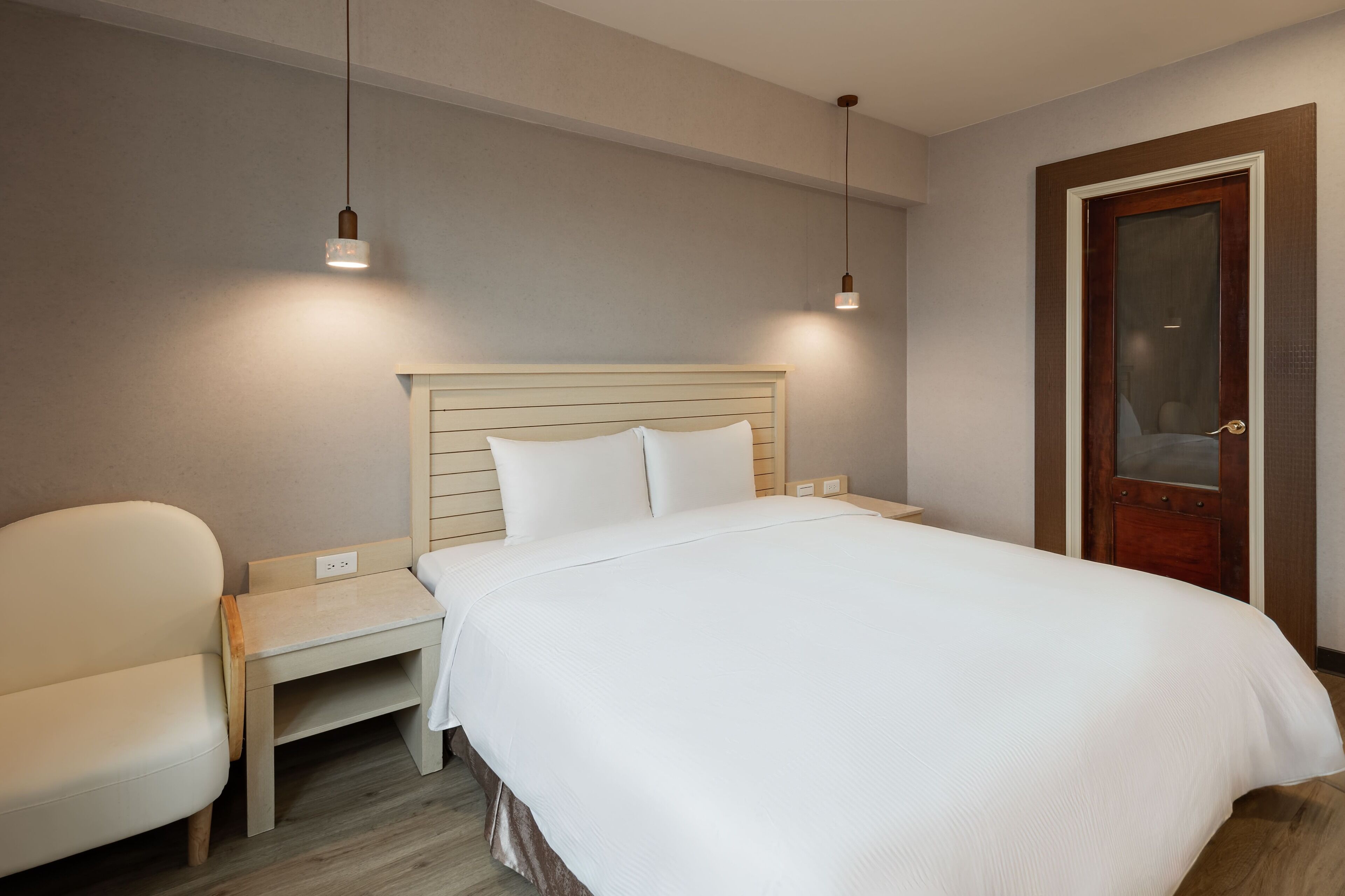 Un dormitorio ordenado con cama, mesita de noche y una silla.