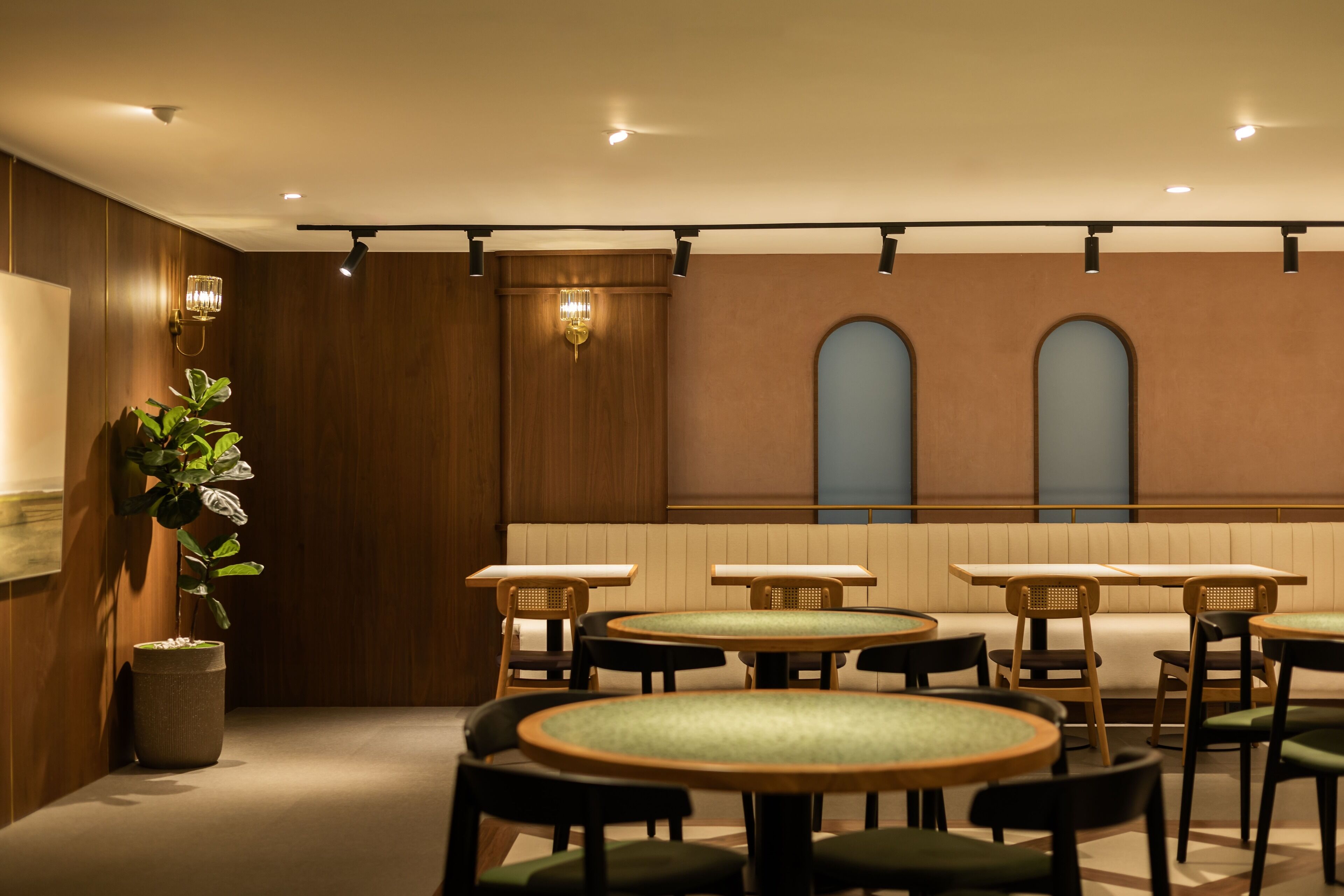 Un restaurante con mesas y sillas redondas, paredes de madera y una planta en maceta.