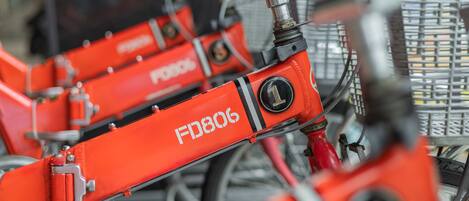 Una fila de bicicletas rojas con la etiqueta 'FD806' en un aparcamiento.