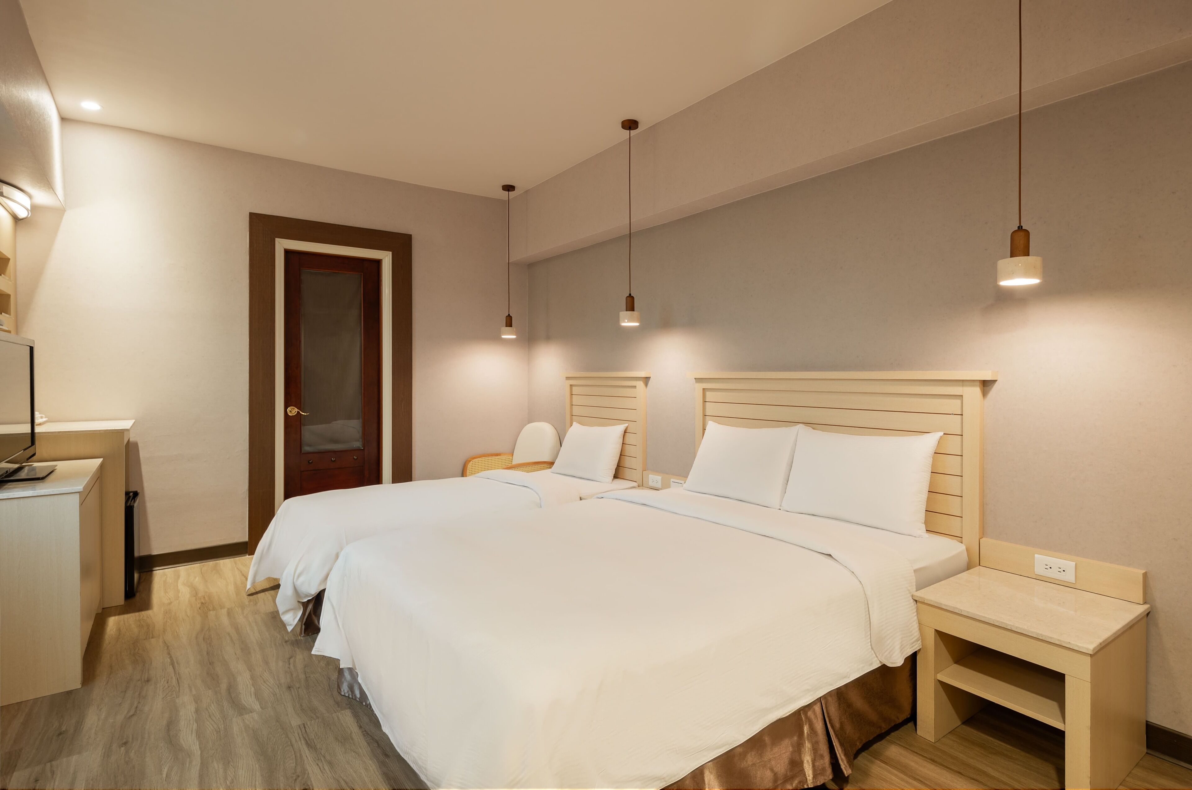 A hotel room with two beds, a desk, and a nightstand.