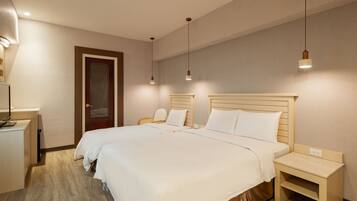 A hotel room with two beds, a desk, and a nightstand.