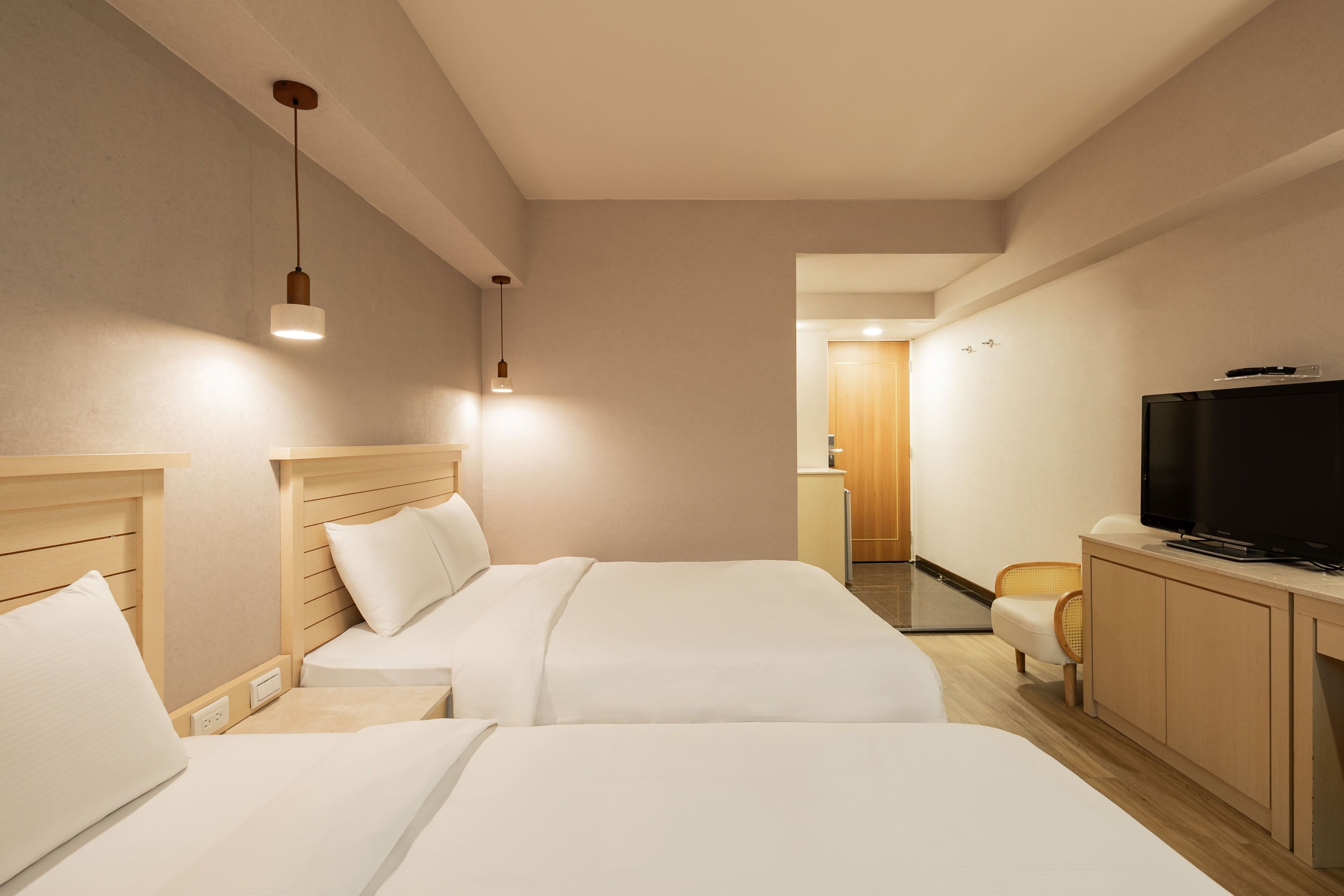 A hotel room with two beds, a TV, a desk, and a chair.