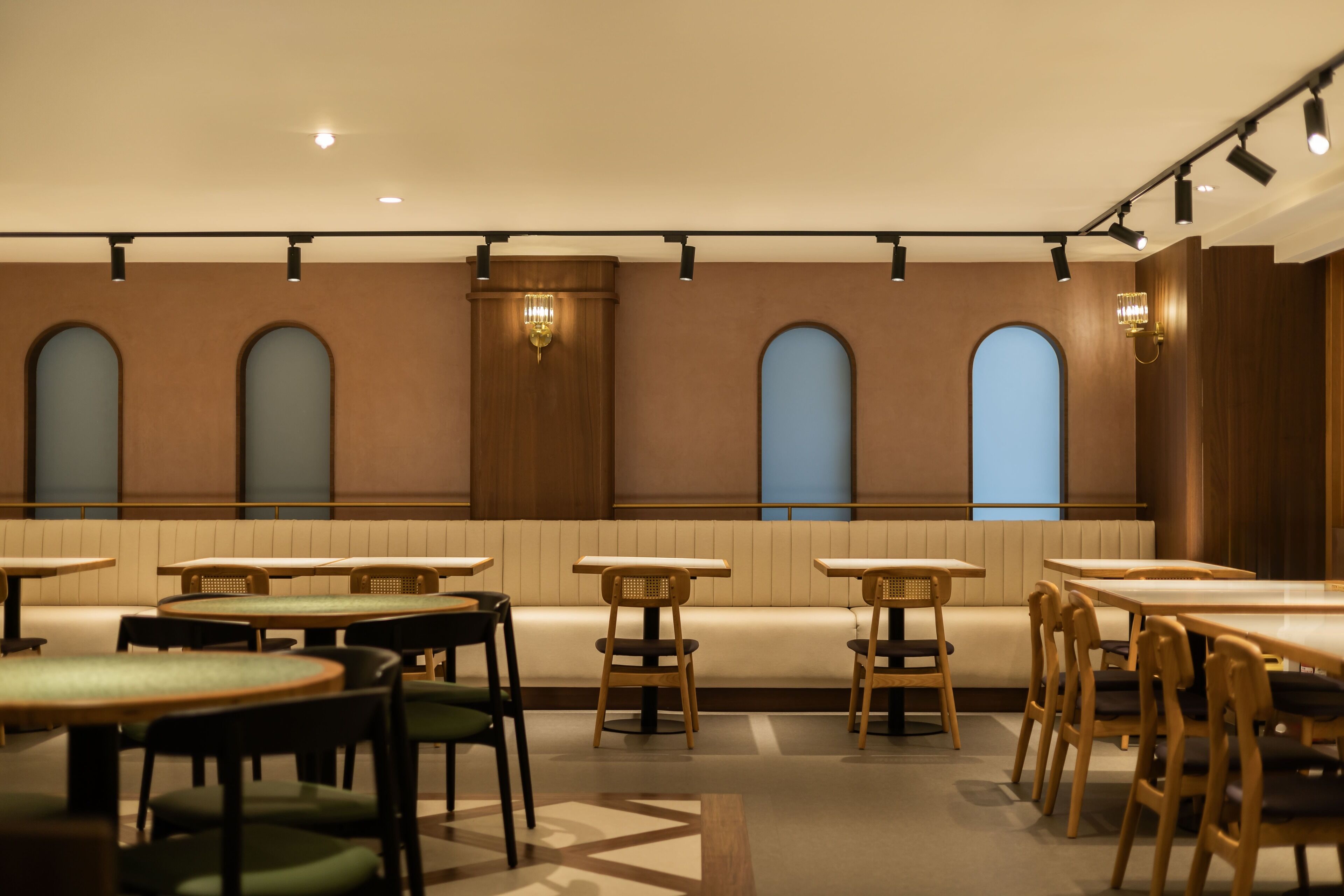 A restaurant with multiple tables and booths, wooden chairs, and a patterned floor.