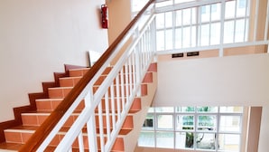 A staircase with wooden handrails and white railings, leading to an upper floor. - Takanta Place (Udon Thani)