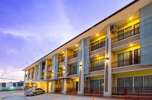 Un hotel de varios pisos con balcones, ventanas amplias y un estacionamiento.