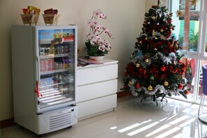 A refrigerator with beverages, a potted orchid, and a Christmas tree with ornaments. - Takanta Place (Udon Thani)