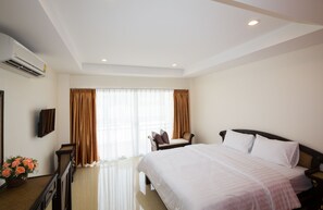 A hotel room with a large bed, a desk with a chair, a TV, and a window with curtains. - Takanta Place (Udon Thani)