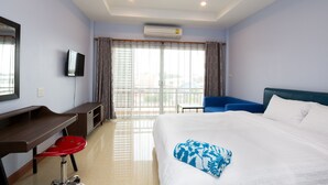 A hotel room with a bed, a desk, a chair, a television, and a balcony with curtains. - Takanta Place (Udon Thani)