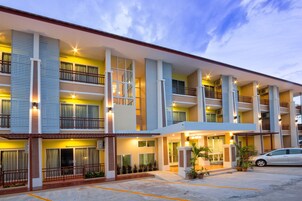 Un hotel de varios pisos con balcones, entrada cubierta y zona de estacionamiento.