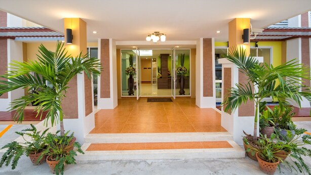 A hotel entrance with a glass door, potted plants, and a tiled floor. - Takanta Place (Udon Thani)