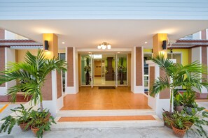 A hotel entrance with a glass door, potted plants, and a tiled floor. - Takanta Place (Udon Thani)