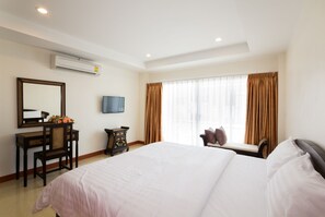 A hotel room with a large bed, a desk with a chair, a television, and a window with curtains. - Takanta Place (Udon Thani)