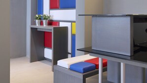 Una habitación moderna con un sofá gris, una mesita con una planta y un televisor sobre un mueble bajo.