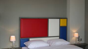 Un dormitorio moderno con una cama grande, un cabecero colorido, lámparas de noche y un colgador de techo.