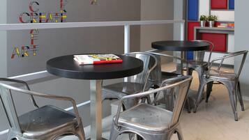 A modern interior with metal chairs and tables, a grey wall with motivational text, and a colorful accent wall.