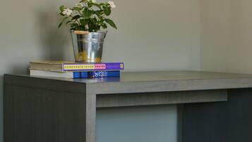 A desk with a metal bucket containing a plant, a stack of books, and a stool.