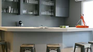 Una cocina moderna con gabinetes grises, una encimera blanca y una barra con taburetes.
