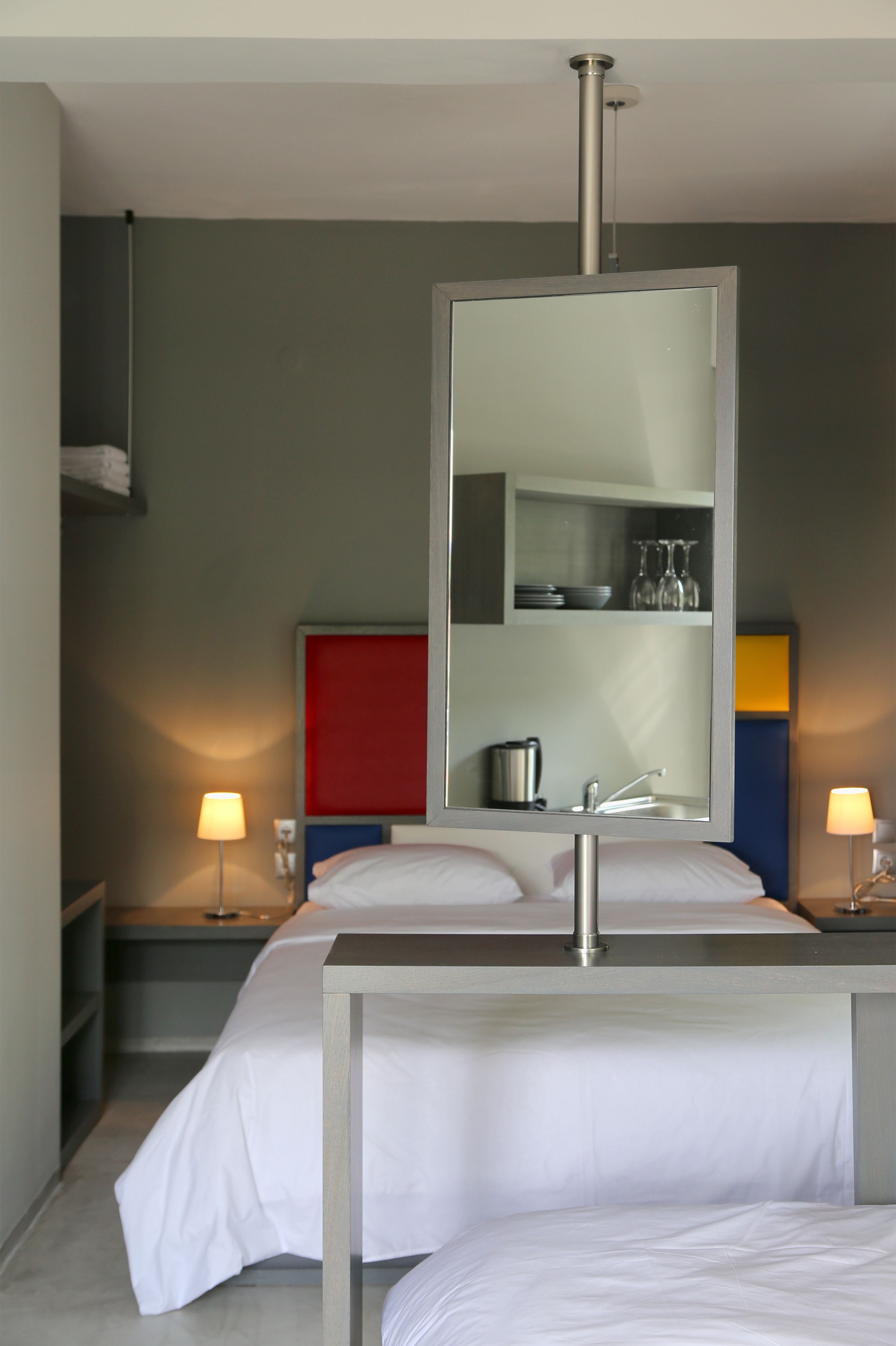 A hotel room with a bed, a large mirror, a sink, and two bedside lamps.
