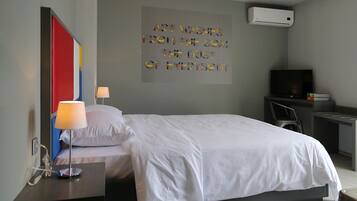 Une chambre d’hôtel moderne équipée d’un lit, d’un bureau avec une lampe, d’une télévision et d’un climatiseur mural.