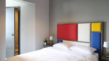 Una camera d'albergo con un letto, un comodino con una lampada e una parete decorata con un motivo colorato.