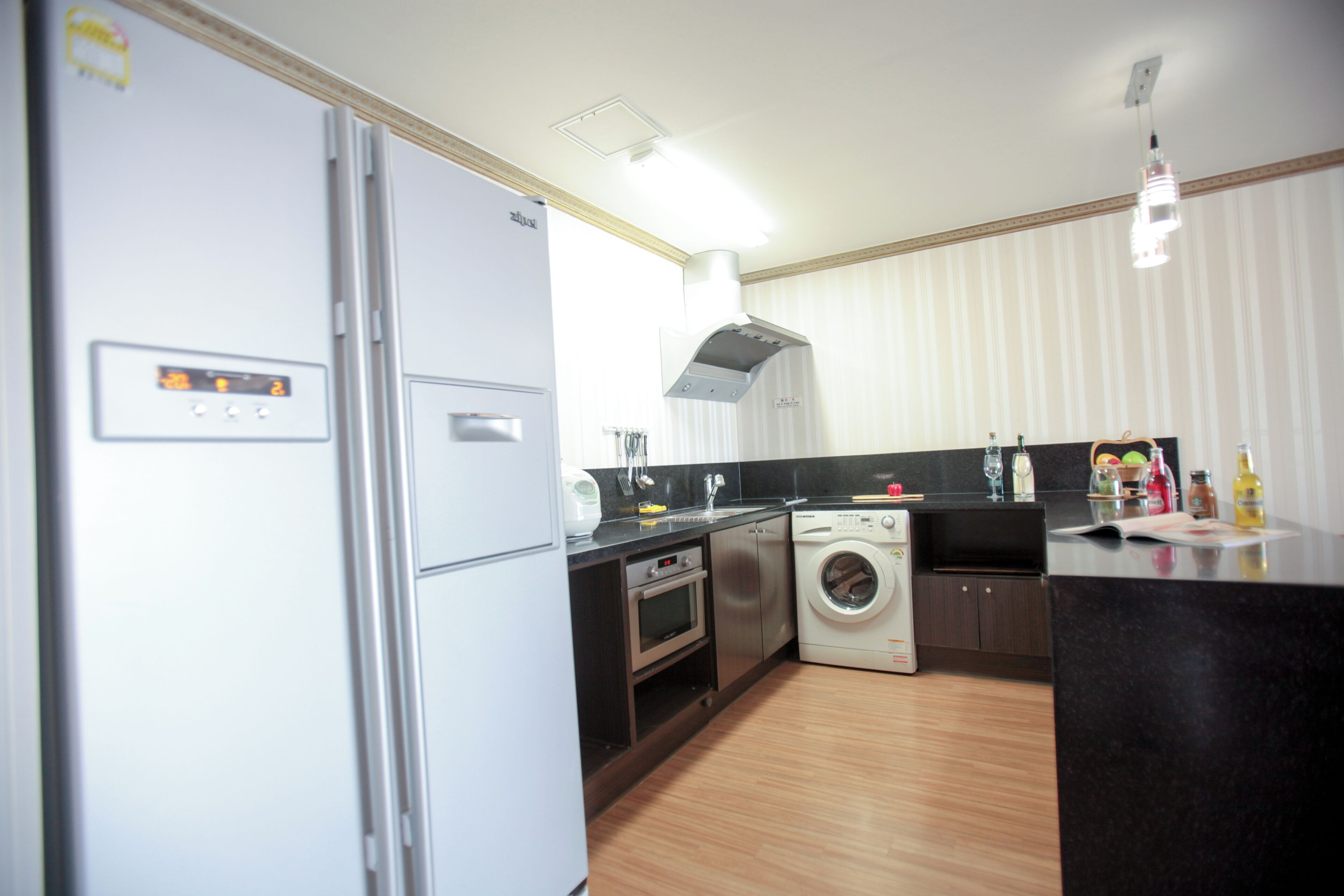 A modern kitchen with a refrigerator, oven, microwave, washing machine, and a sink.