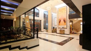 A spacious lobby with a staircase, large windows, and a central column.