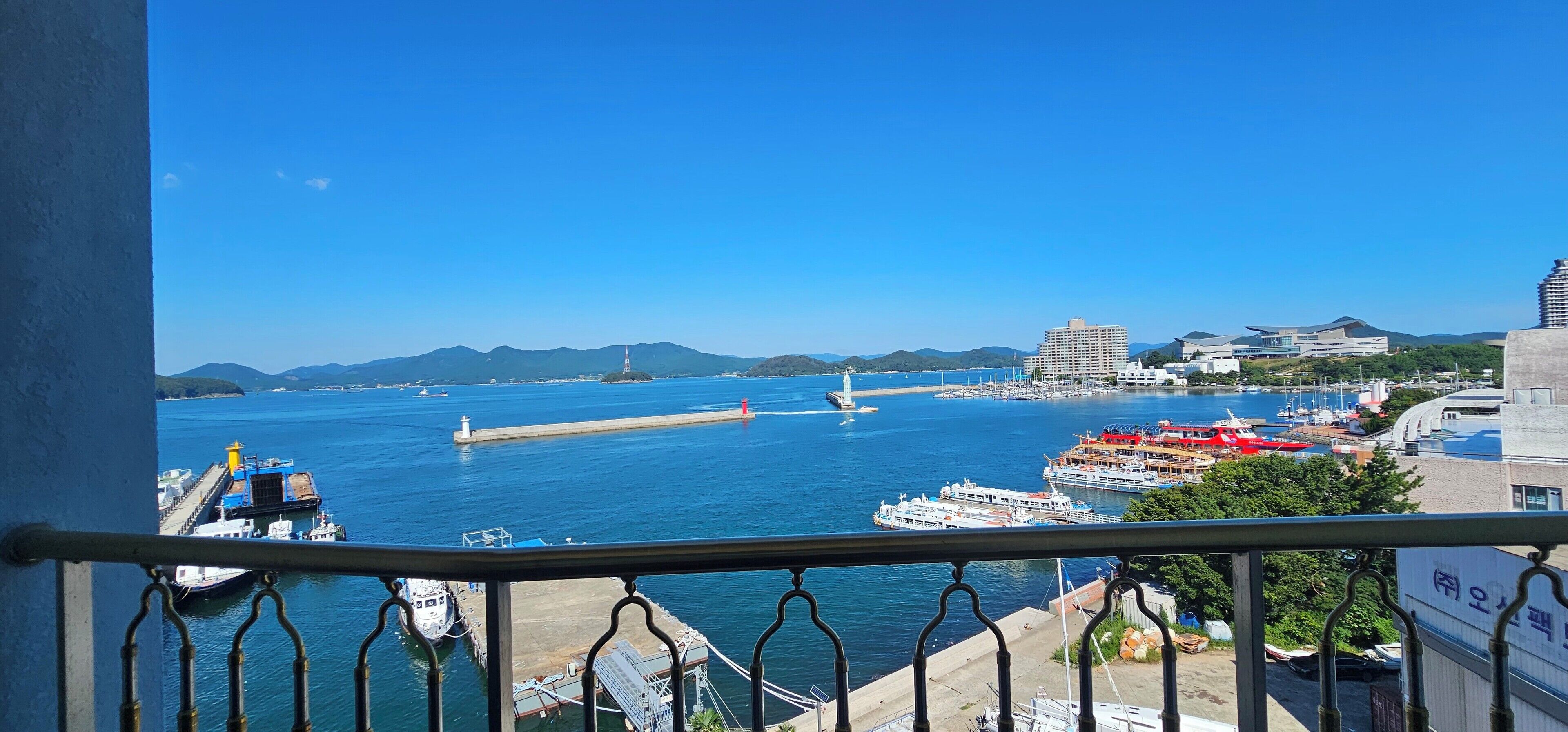 A coastal cityscape with a harbor, boats, and buildings.