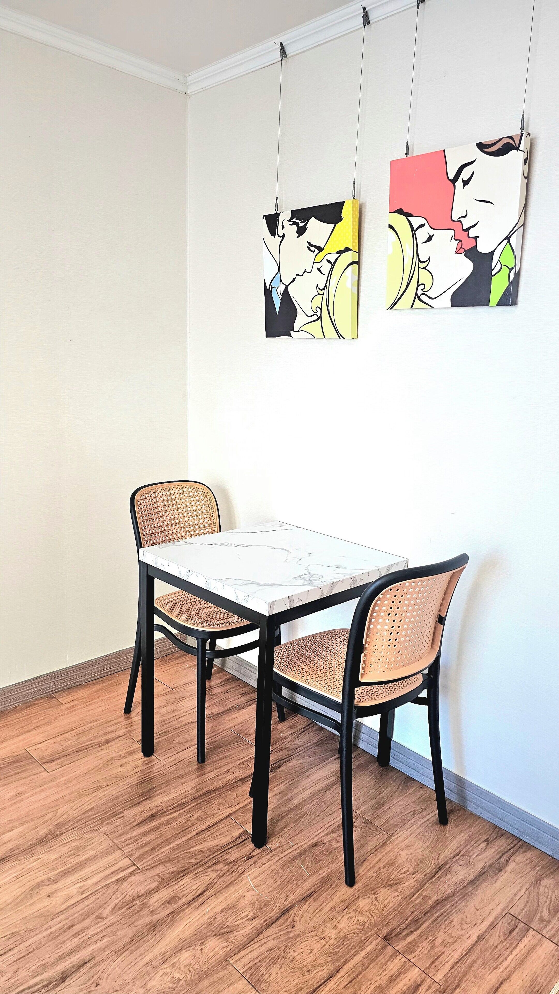 Un coin repas avec une table en marbre et deux chaises en osier.