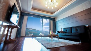 A modern living room with a large window, a sofa, a coffee table, and a television.