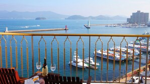 A balcony with a view of the sea, boats, and a distant island.