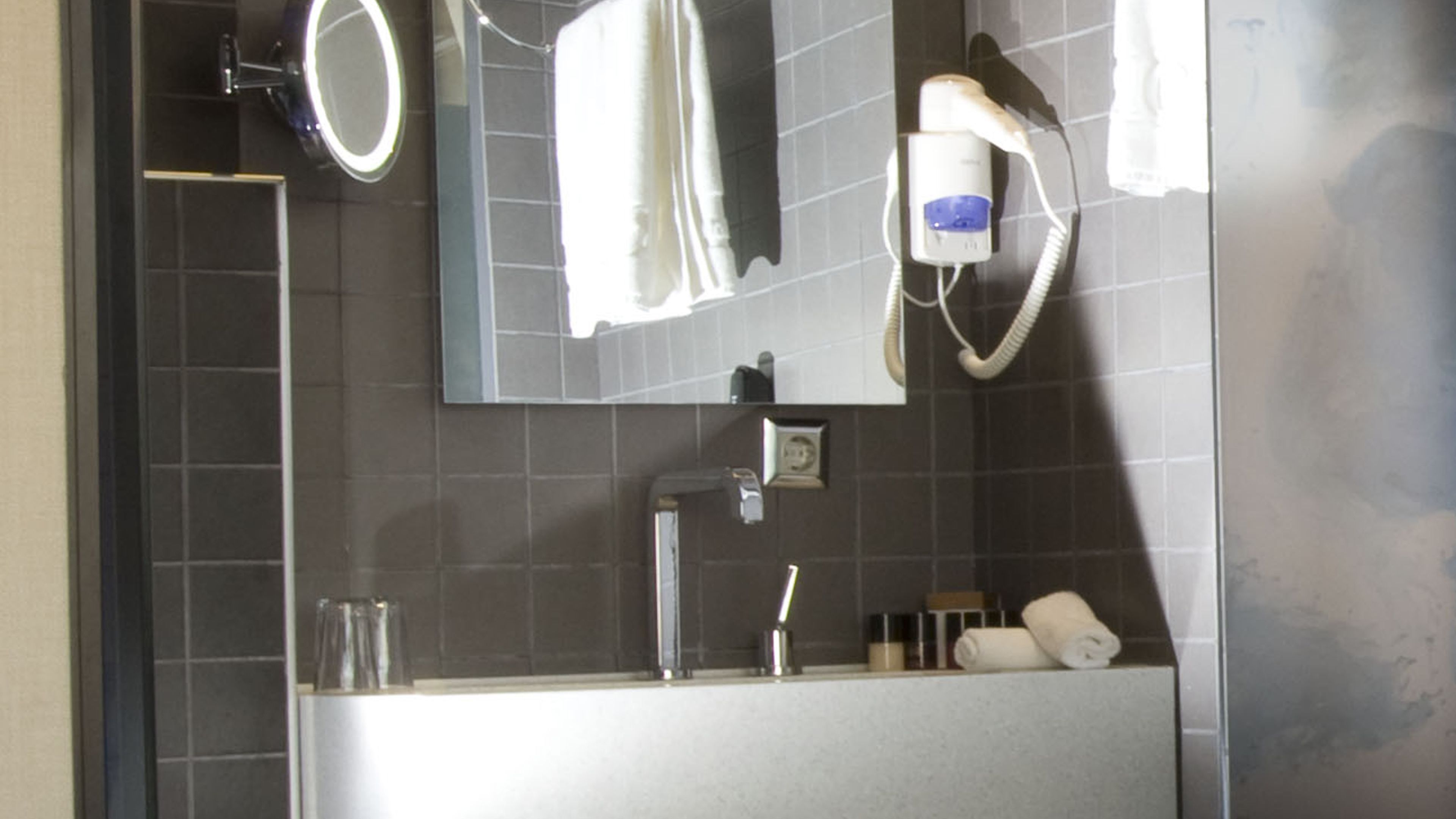 A bathroom with a sink, mirror, towel rack, and a hairdryer.