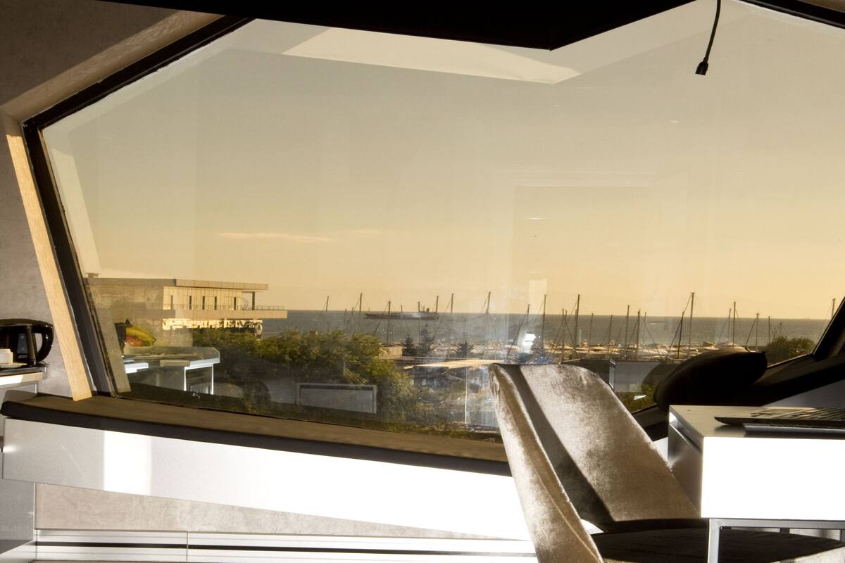 A modern room with a large window overlooking a marina and boats.