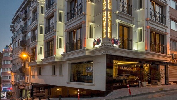 Un hotel de varios pisos con un llamativo letrero iluminado que dice 'Prilis Gold Hotel'.