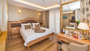 Una habitación de hotel con una cama grande, mesitas de noche, un escritorio con lámpara y un espejo.