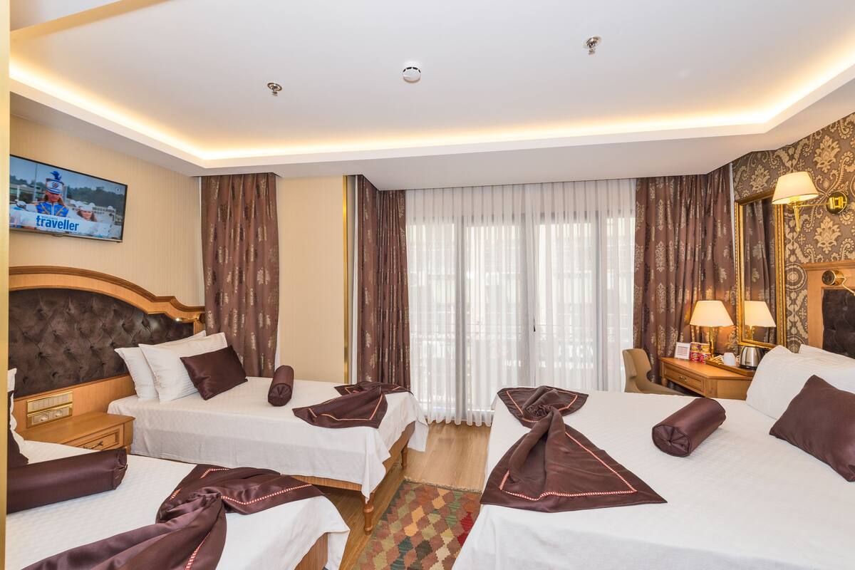 A hotel room with two beds, a television, a desk, and a mirror.