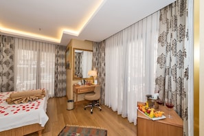 A hotel room with a bed, desk, and a fruit basket with drinks. - Aprilis Gold Hotel - Special Class (Istanbul)
