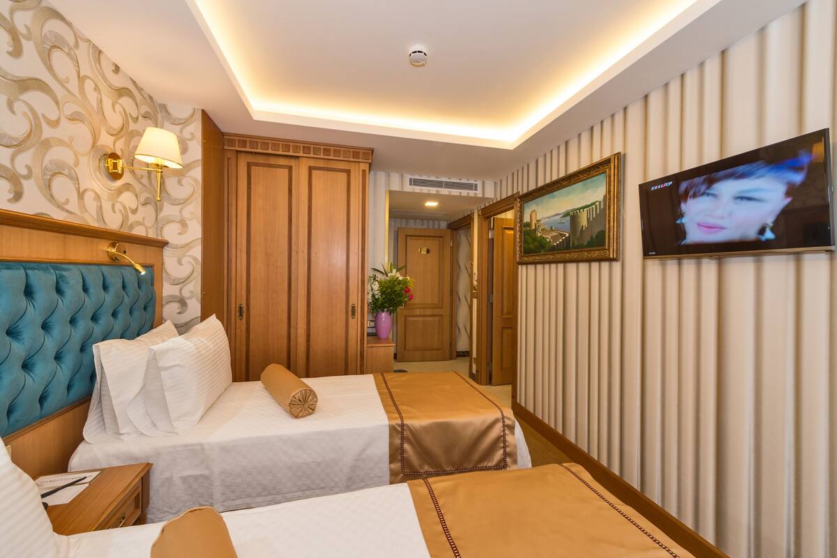 A hotel room with two beds, a television, and a decorative wall.