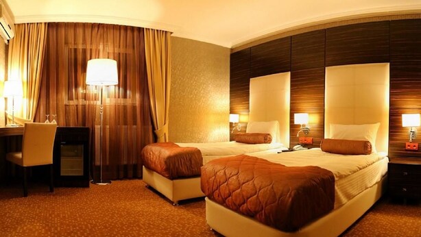 A hotel room with two beds, a desk, and a chair. - Rota Bulvar Hotel (Ankara)