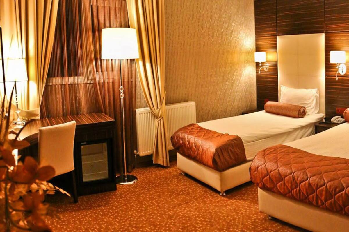 Habitació d'hotel amb dos llits, un escriptori i una cadira.