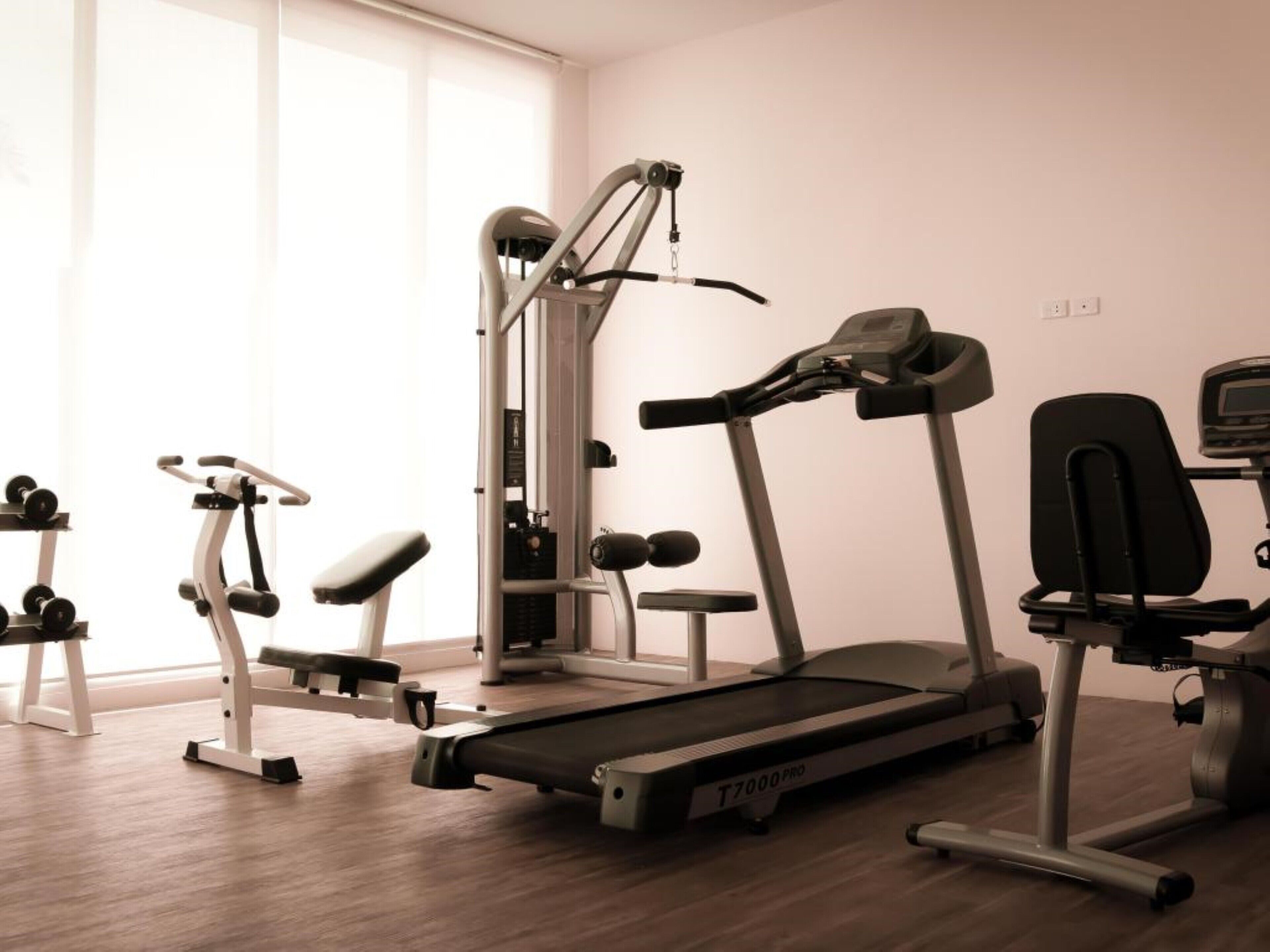 Ett gym med konditionsmaskiner, styrketräningsmaskiner och en träningsbänk.