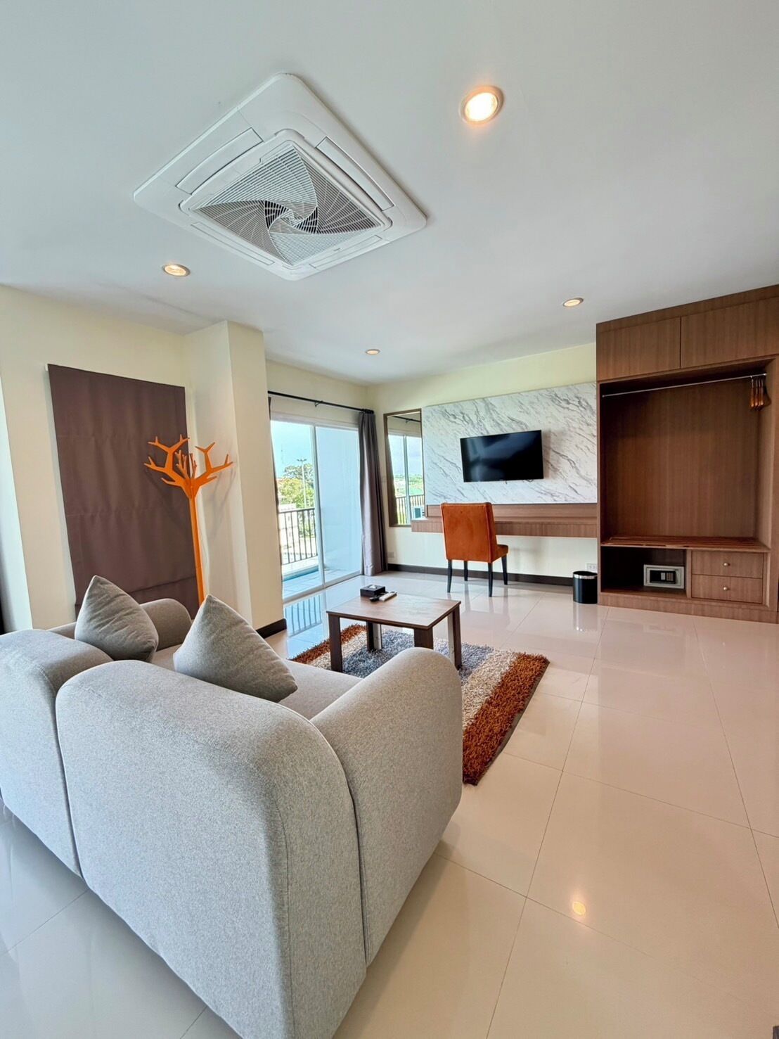 A modern living room with a sofa, a TV, a fireplace, and a balcony.