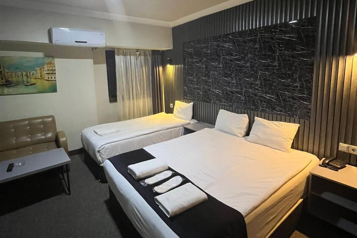 A hotel room with two beds, a desk, a chair, and a large wall mural.