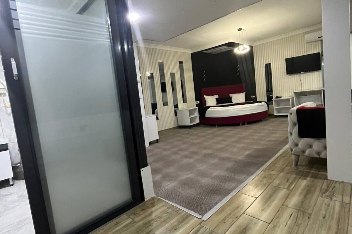 A hotel room with a large bed, a TV mounted on the wall, and a sliding door leading to a bathroom.