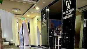 Entrada de un hotel con un letrero negro que dice "KOZAMILENYUM HOTEL & SPA RESTAURANT".