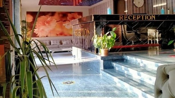 Zona de recepción con mostrador, un reloj y una escalera que lleva a un nivel superior.