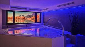 A modern indoor swimming pool with a panoramic window view of autumn foliage and mountains. - Hotel Mirabel (Marebbe)