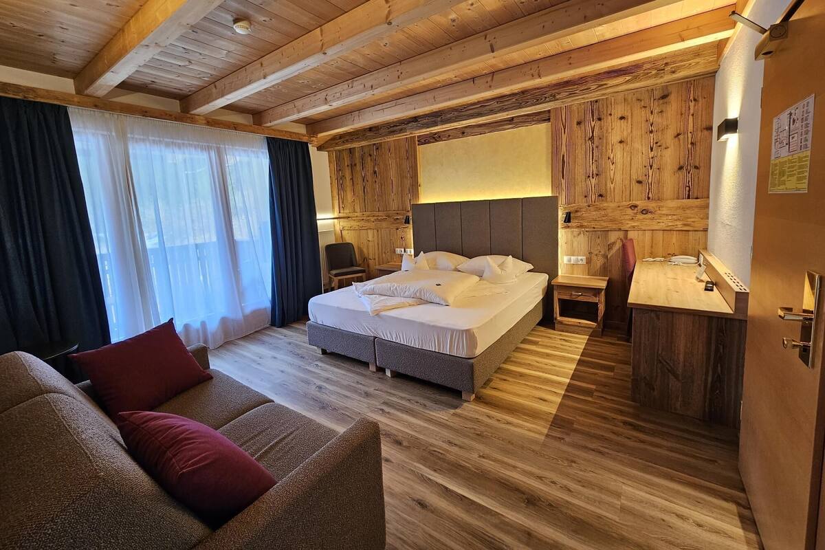 Un dormitorio con paneles de madera, una cama, una mesita de noche y un sofá.