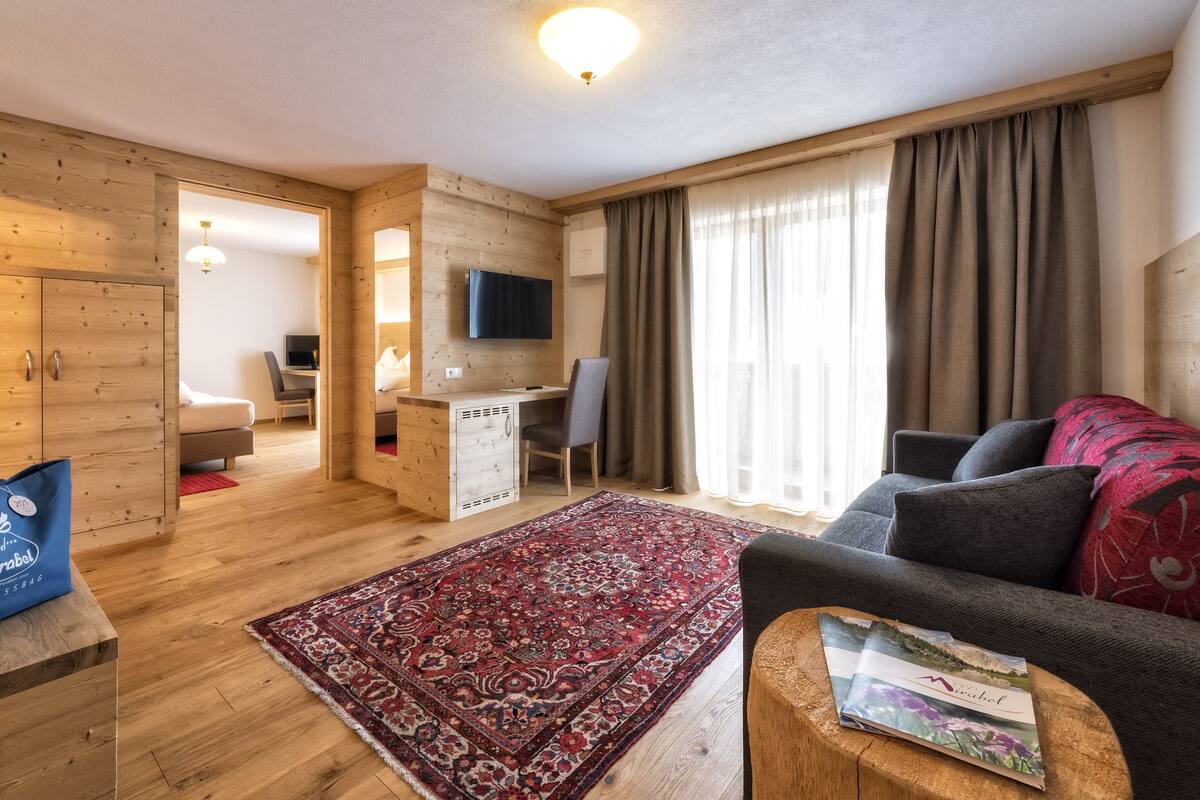 Una habitación de hotel moderna con paredes de madera, un sofá, un escritorio y un televisor.