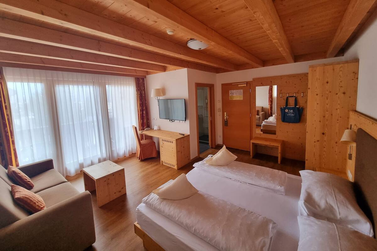 Una habitación tipo cabaña de madera con una cama, un escritorio y una silla.