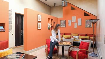 A room with orange walls, a sofa, a table with a chessboard, and a door.